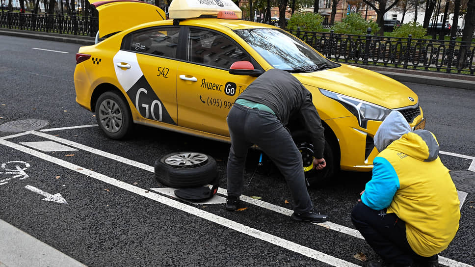Водитель такси меняет колесо у автомобиля на Тверском бульваре