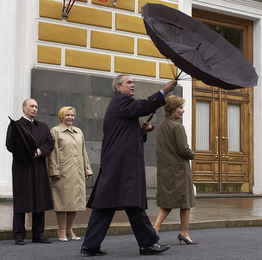Президент России Владимир Путин (на заднем плане) и бывший президент США Джордж Буш с супругами во время визита в Москву по случаю Парада на Красной площади в мае 2005 года.