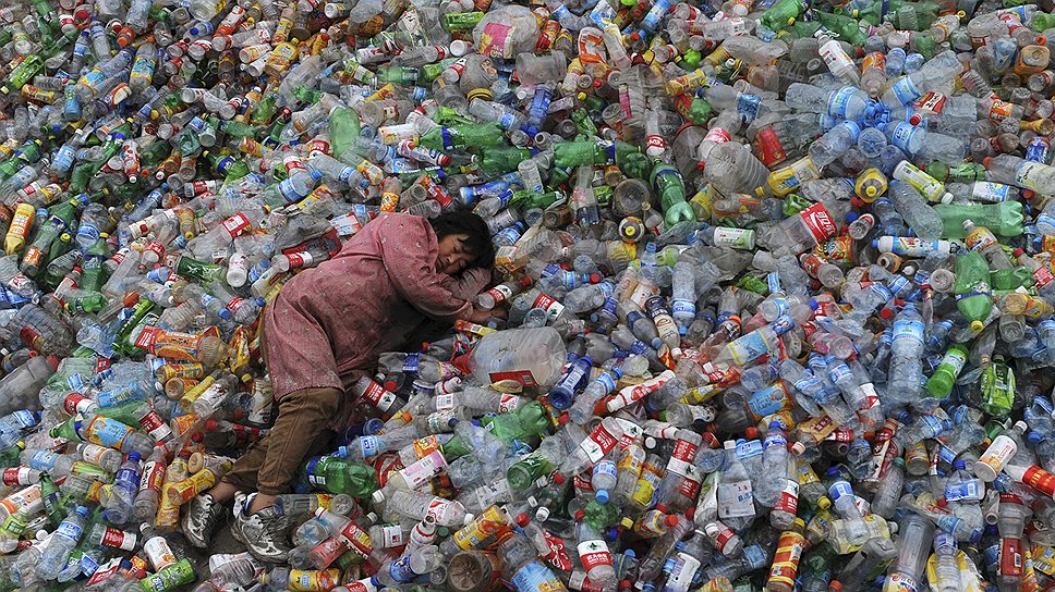 Рабочий на горе из пластиковых бутылок в перерабатывающем центре в Цзясине (Китай), ноябрь 2011 года