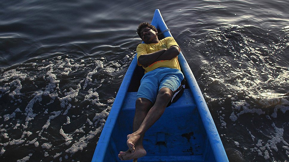 Волонтер во время индийского фестиваля Ганеши в лодке на берегу Аравийского моря, сентябрь 2012 года