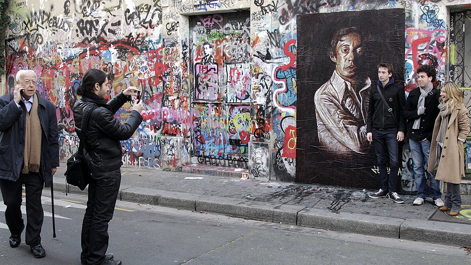 Люди рядом с граффити и картинами Сержа Генсбура на стене дома музыканта на улице Верней в Париже. 2 марта 2011 года — тогда фанаты праздновали 20-ю годовщину смерти Генсбурга 