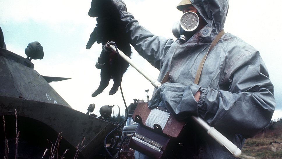 Мужчина в защитном костюме проверяет уровень радиации у домашних животных в зараженной зоне