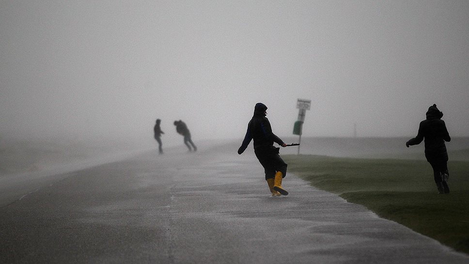 Люди гуляют на берегу Северного моря на сильном ветру, который ураган «Ксавер» принес на северное побережье Германии 