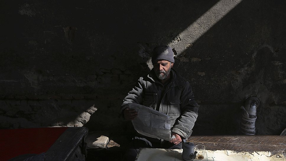 Житель Кабула читает газету в чайной