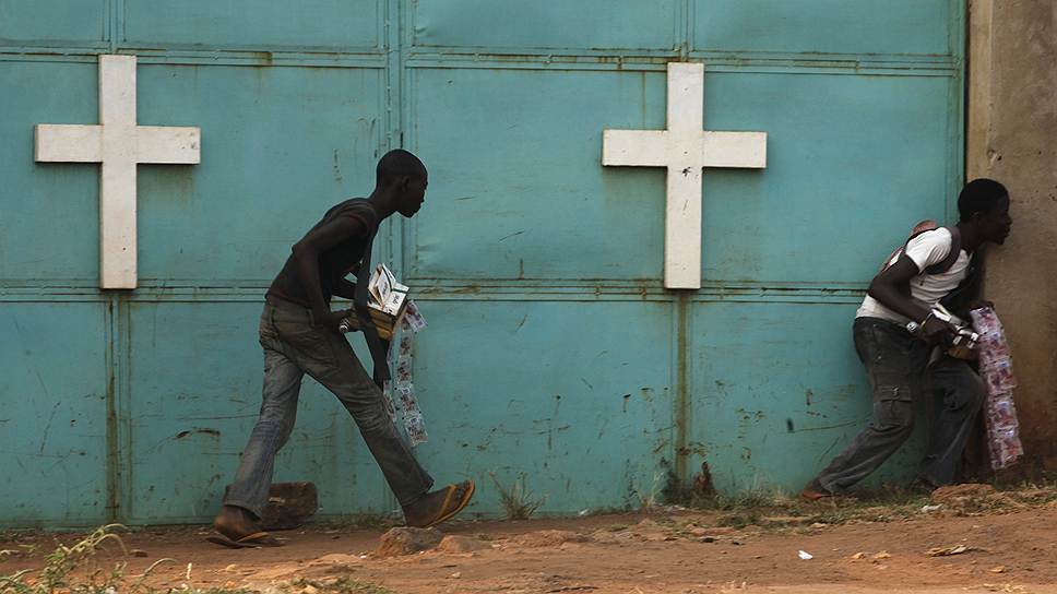Местные жители укрываются от огня у церкви во время боестолкновений между африканскими миротворцами и христианскими повстанцами в Банги, ЦАР