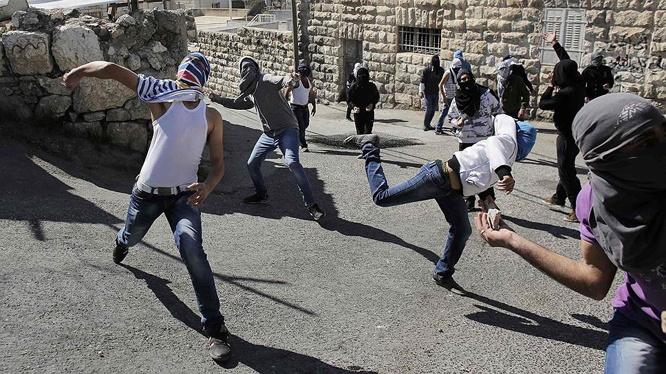 Палестинцы забрасывают израильских полицейских камнями во время столкновений в в арабском районе Иерусалима Рас-аль-Амуд