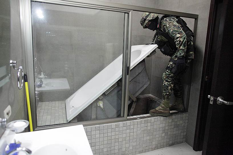 Мексиканский морской пехотинец показывает журналистам секретный вход в туннель, ведущий из дома арестованного наркобарона Хоакина &quot;Чапо&quot; Гусмана в город Кульякан