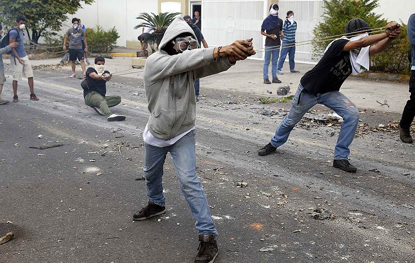 Демонстранты стреляют из импровизированной рогатки во время антиправительственных протестов в Каракасе