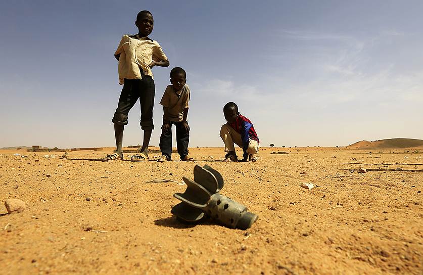 Суданские дети смотрят на хвост минометного снаряда, найденного после атаки повстанцев в Северном Дарфуре