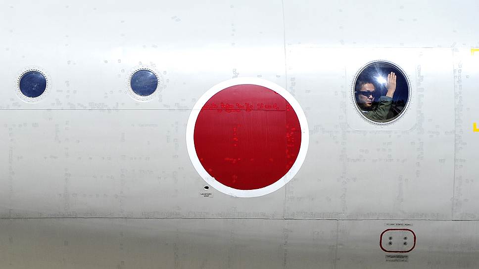 Член экипажа австралийского военного самолета машет журналистам перед вылетом с военной базы недалеко от Перта на поиски пропавшего авиалайнера Malaysia Airlines
