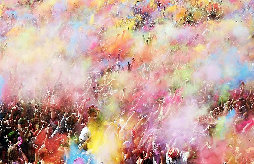 Люди бросают цветной порошок в ходе фестиваля Холи в Барселоне