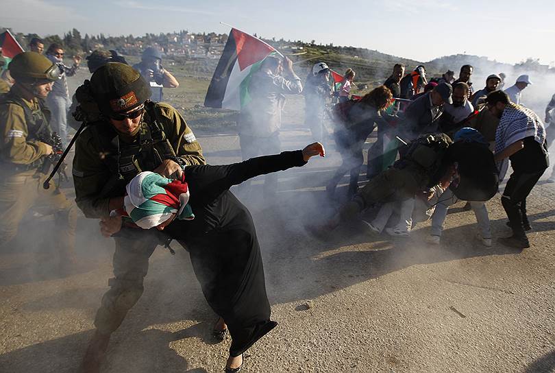 Израильский солдат задерживает палестинку во время акции протеста недалеко от Рамаллаха