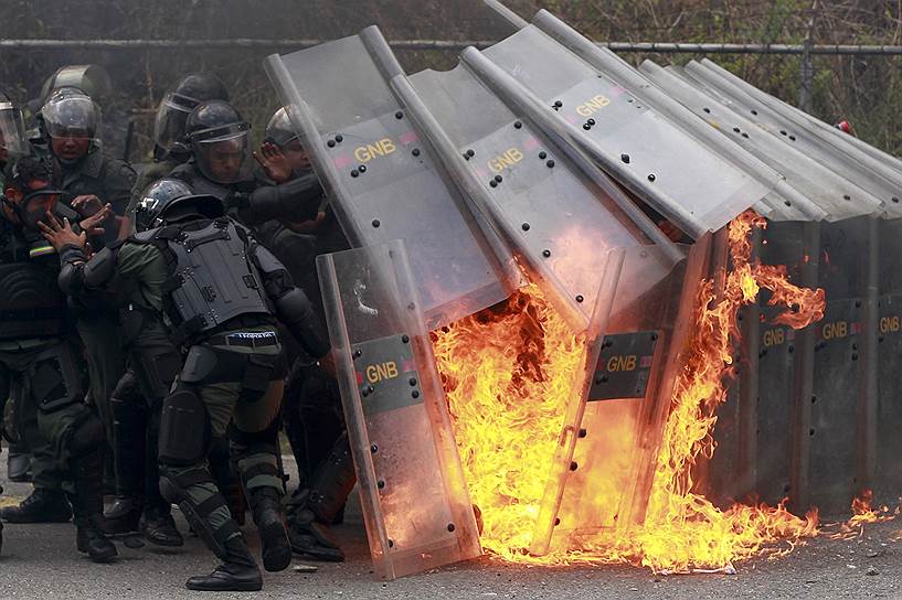 Сотрудники венесуэльской полиции спасаются от «коктейля Молотова», брошенного протестующими в Каракасе