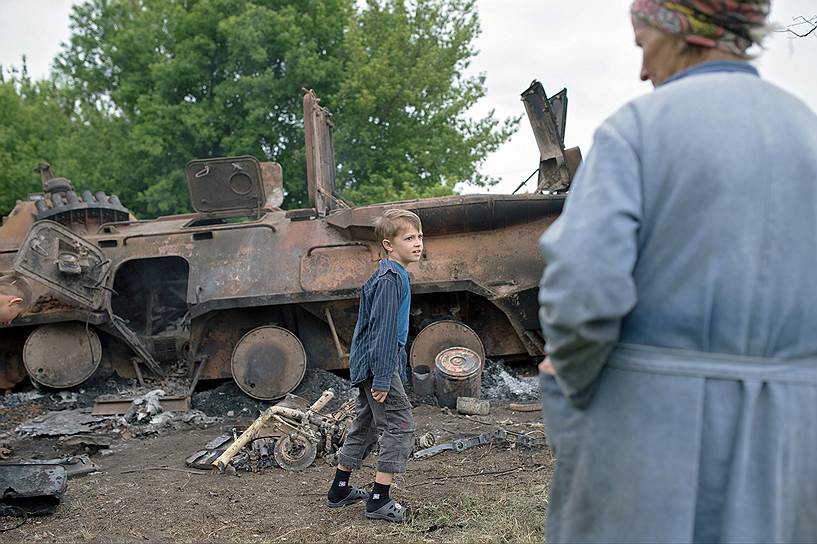 Местные жители осматривают сгоревшую военную технику на въезде в Славянск
