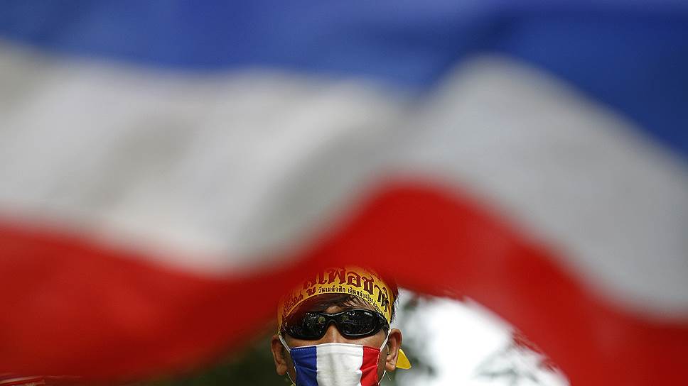 Участник антиправительственного протеста с национальным флагом во время митинга в Бангкоке