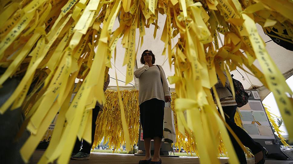 Женщина читает записки на лентах в мэрии Сеула, посвященные погибшим и пропавшим пассажирам парома Sewol, затонувшего у берегов Южной Кореи