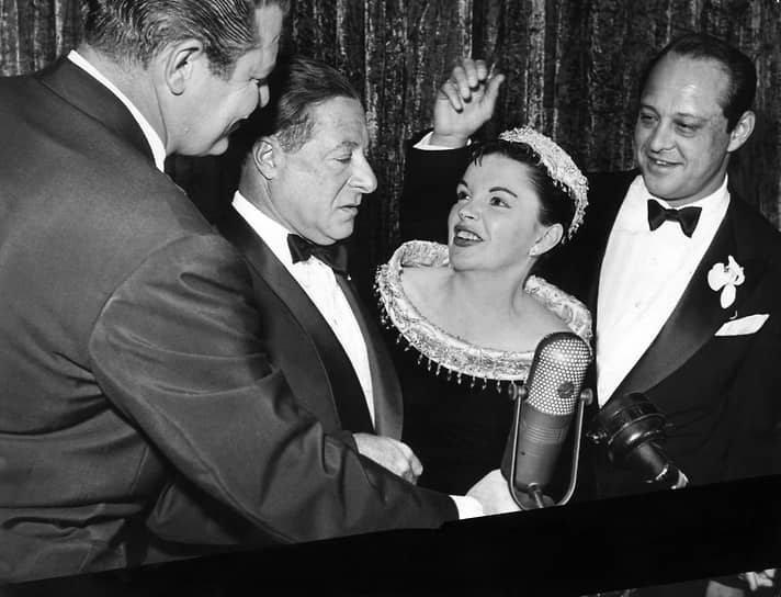 Голливудский актер и певец Джордж Джессел, с которым у сестер было совместное выступление в чикагском «Восточном театре», оказал влияние на карьеру будущей звезды Голливуда. Именно он помог выбрать актрисе более подходящий сценический псевдоним — Джуди Гарленд
&lt;br> На фото (слева направо): актеры Джек Карсон, Джордж Джессел, Джуди Гарленд и ее муж Сидни Люфт, 1954 год