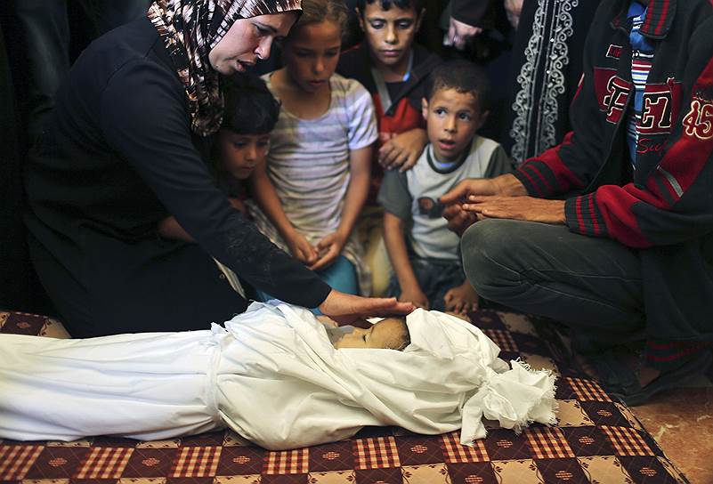 Мать прощается со своей маленькой дочерью на церемонии похорон. Трехлетняя палестинская девочка погибла во время взрыва в секторе Газа, трое членов ее семьи получили ранения. Ответственность за теракт возложили на Израиль