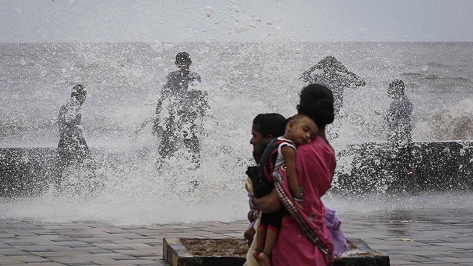 Люди наслаждаются водой во время морского прилива в Мумбаи, где редкие дожди в начале июня практически привели к засухе