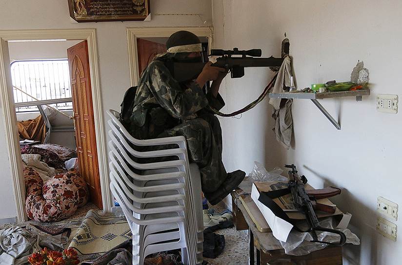 Сирийский повстанец целится сквозь дыру в стене дома в Мореке, мухафаза Хама