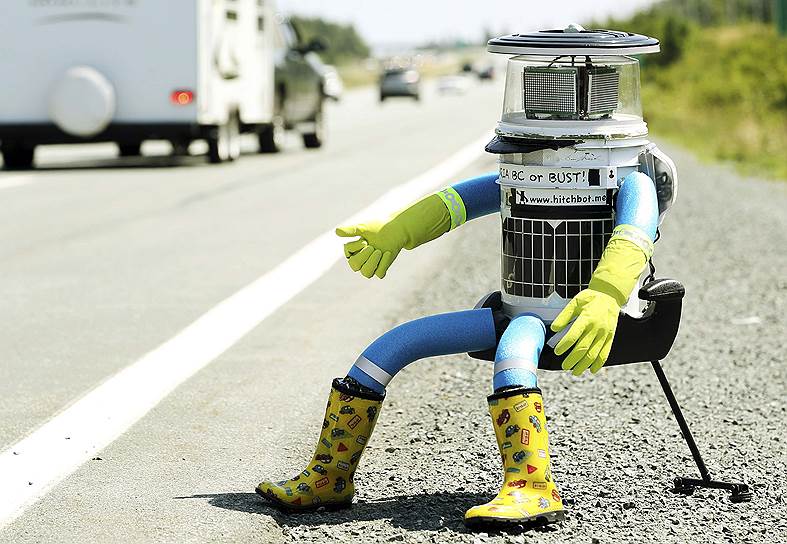 Антропоморфный робот-автостопщик hitchBOT на обочине шоссе в Канаде — социальный эксперимент, в рамках которого исследователи увидят, подбросят ли водители робота-автостопщика в целости и сохранности до арт-галереи в Виктории