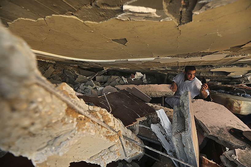 09.07.14. Палестинец в поисках своих вещей под руинами дома