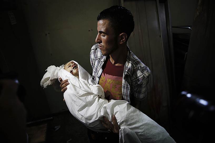 23.07.14. Палестинец держит на руках тело двухлетней девочки, погибшей при танковом обстреле в Бейт-Лахии