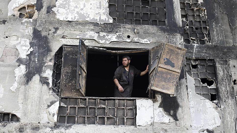 Палестинский рабочий выглядывает из окна фабрики в провинции Дейрл эль-Балах в центральной части сектора Газа, разрушенной в ходе израильской атаки