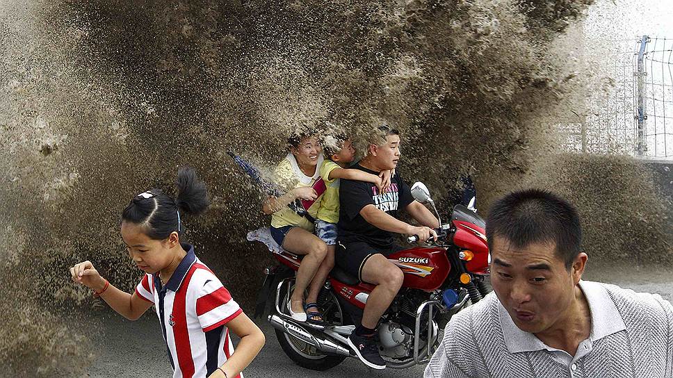 Люди спасаются от приливной волны на набережной в Ханчжоу, провинция Китая Чжэцзян