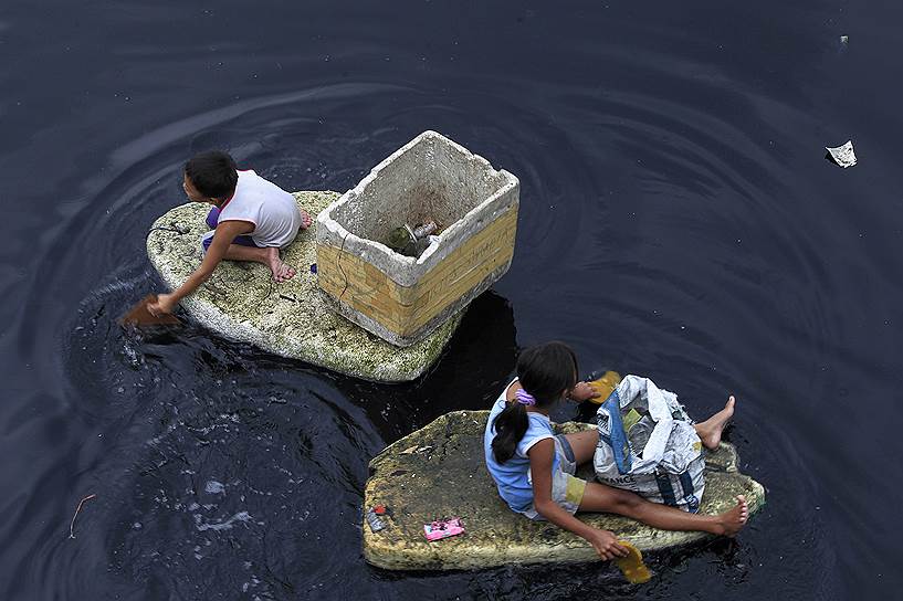 Филиппинские дети на самодельных пенопластовых лодках во время сбора пластика, пригодного для переработки, в Манильском заливе