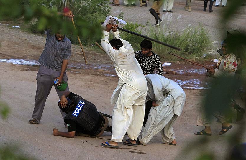 Демонстранты избивают полицейского после столкновений во время «Марша революции» в Исламабаде