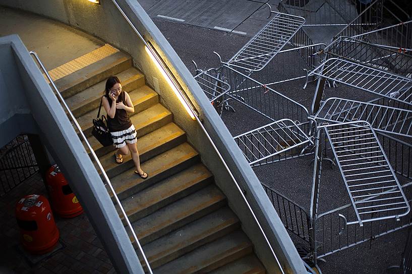 Женщина проходит рядом с баррикадами из ограждений в Гонконге