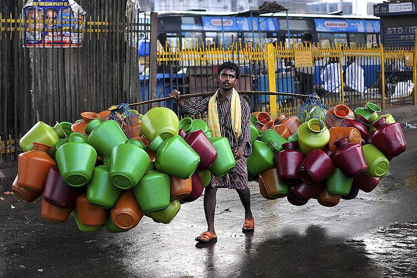 Индиец несет емкости для воды на продажу на рынок в Бангалоре