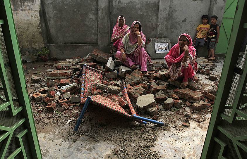 Крестьяне сидят на развалинах своего дома после того, как он был поврежден во время недавней перестрелки между Пакистаном и Индией на пакистанской границе