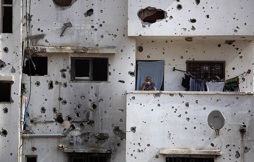 Палестинец на балконе своего дома в Газе, частично разрушенного во время войны с Израилем