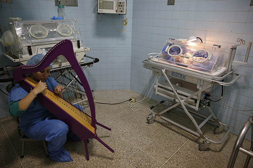 Сотрудница венесуэльской музыкальной образовательной программы «Эль Система» играет на арфе в родильном отделении больницы в Каракасе