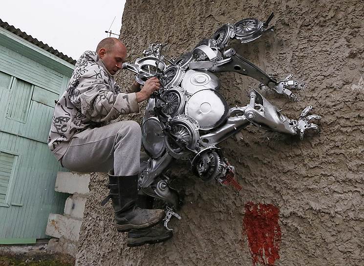 Автомеханик из Дивногорска Сергей Кулагин проверяет крепление одной из своих скульптур, созданных из автомобильных запчастей 
