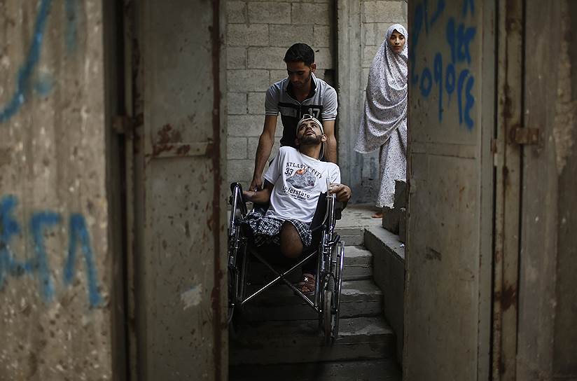 Брат палестинца, потерявшего обе ноги во время конфликта с Израилем, помогает ему добраться до своего дома в Бейт-Лахии, сектор Газа