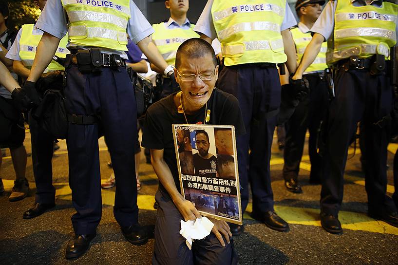 Активист с фотографией госпитализированного участника митинга в Гонконге 