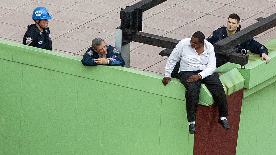 Мужчина, угрожая покончить с собой, сидит на краю крыши высотного здания в Нью-Йорке на Таймс-сквер. Позднее полицейские уговорили его не прыгать