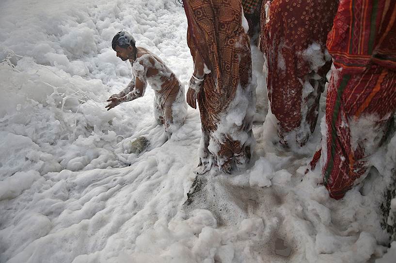 Индуисты во время обряда поклонения богу Солнца Сурье в загрязненных водах реки Джамна в Нью-Дели