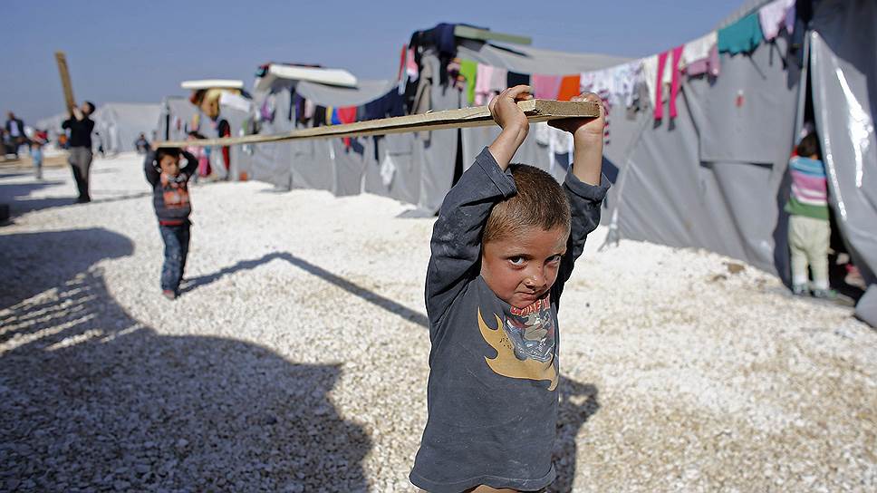 Курдские дети, эвакуированные из города Кобани, несут доску в лагере беженцев, расположенном на сирийской границе