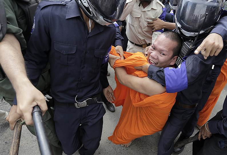 Буддийский монах задержан камбоджийской полицией во время акции протеста перед городским судом, с призывами к суду освободить семерых задержанных протестующих, в Пномпене