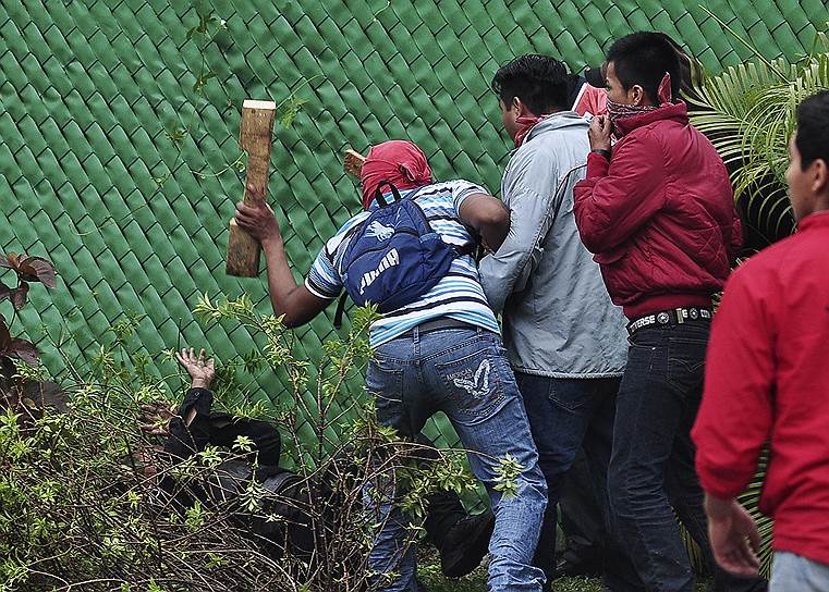 Протестующий бьет лежащего полицейского во время во время беспорядков, вызванных гибелью 43 студентов, в Акапулько