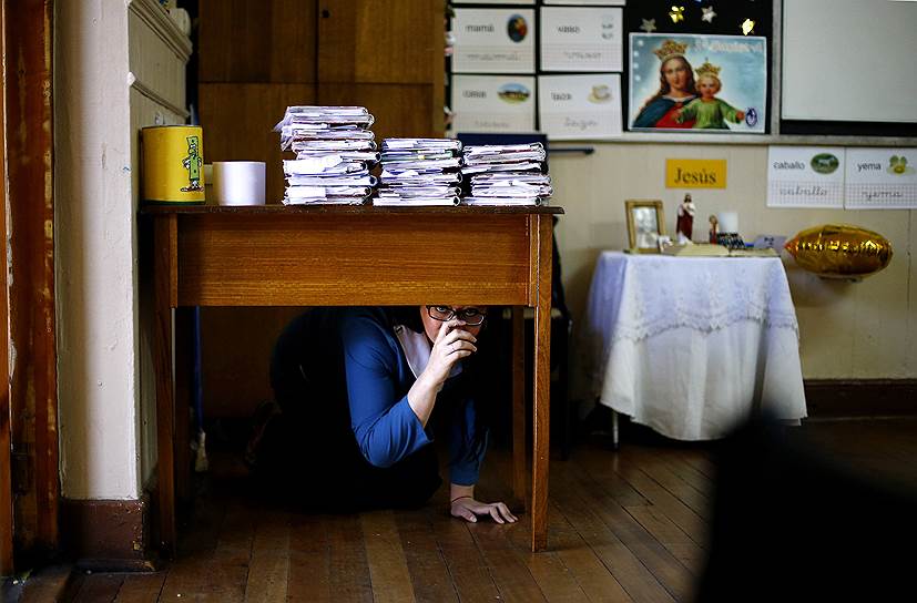 Сантьяго, Чили. Учитель прячется под столом в школе в рамках отработки правил поведения при угрозе землетрясения