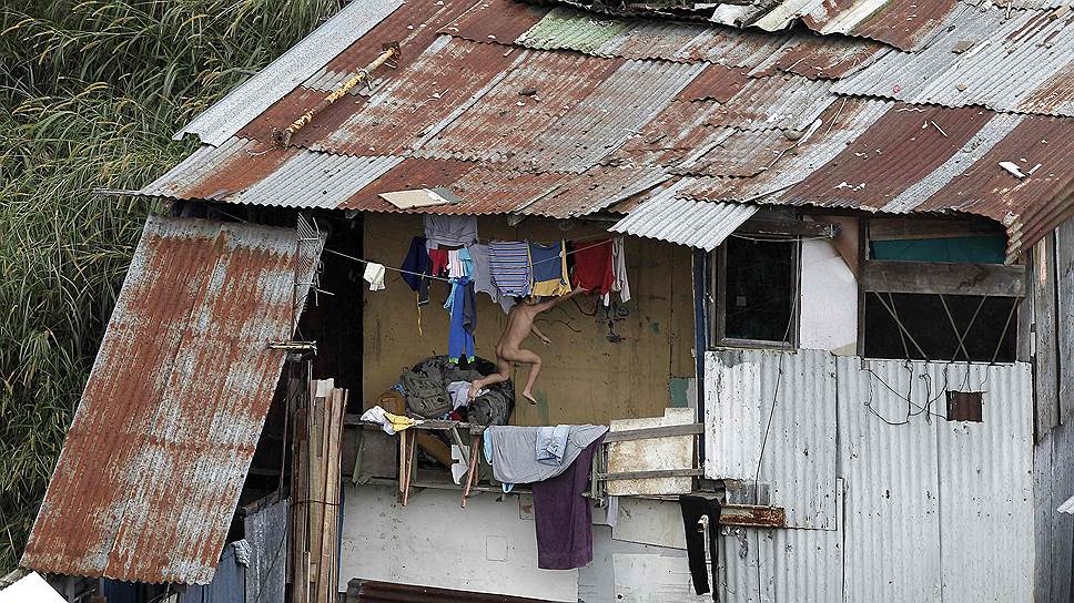 Сан-Хосе, Коста-Рика. Мальчик пытается достать футболку с бельевой веревки на балконе своего дома в трущобном районе города