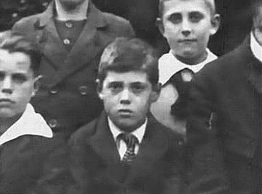 Адольф Эйхман (на фото в 4-м классе гимназии) родился в 1906 году. За маленький рост и темные волосы в Обществе христианской молодежи, где состоял Эйхман, его дразнили «маленьким евреем», что раздражало мальчика. Из-за непростого характера и плохой успеваемости отец забрал его на работу на собственную шахту, где Эйхман проработал около трех месяцев, затем начал изучать электротехнику. В 1932 году он вступил в СС и переехал из Австрии, где запретили деятельность партии, в Германию. Вскоре он поступил на работу в Службу безопасности рейсхфюрера СС Гиммлера, где занимался разбором канцелярии.  Во второй половине 1935 года унтерштурмфюрер СС барон Леопольд Иц Эдлер фон Мильденштайн предложил Эйхману перейти в только что организованный им отдел «евреи» в Главном управлении СД. Мильденштайн поручил Адольфу составить справку по книге «Еврейское государство» Теодора Герцля, которая затем использовалась как служебный циркуляр для внутреннего пользования в СС