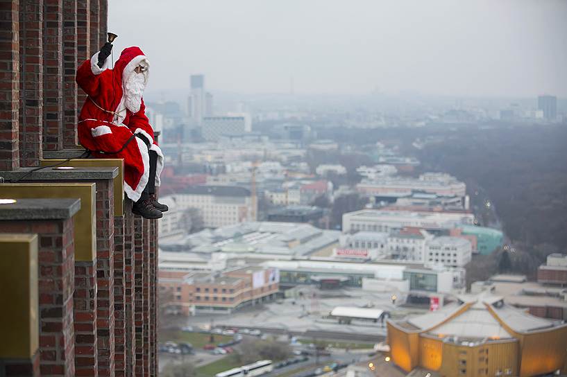 Берлин, Германия. «Санта-Клаус», позирующий журналистам на Кольхофф-тауэр, высотном здании на Потсдамской площади