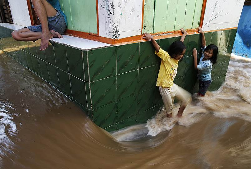 Джакарта, Индонезия. Дети пытаются пробраться по затопленной улице в жилом районе Джакарты