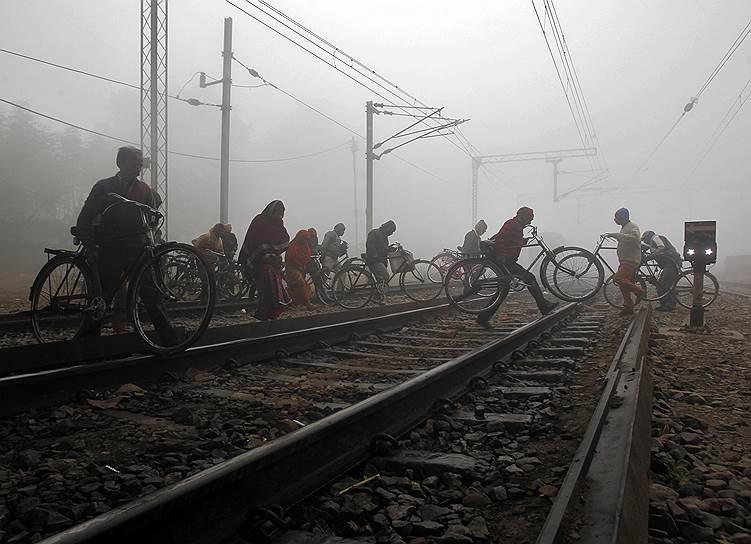 Аллахабад, Индия. Люди с велосипедами пересекают железнодорожные пути
